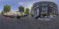 a fish eye lens photograph of a residential area in europe and the street is filled with parked cars and pedestrians