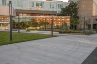 a city street surrounded by grass and tall buildings at the end of a street there is a paved pathway in front of the building