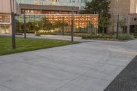 a city street surrounded by grass and tall buildings at the end of a street there is a paved pathway in front of the building