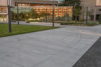 a city street surrounded by grass and tall buildings at the end of a street there is a paved pathway in front of the building