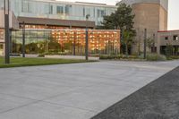 a city street surrounded by grass and tall buildings at the end of a street there is a paved pathway in front of the building