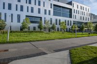 a city street surrounded by grass and tall buildings at the end of a street there is a paved pathway in front of the building