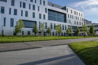 a city street surrounded by grass and tall buildings at the end of a street there is a paved pathway in front of the building