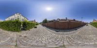 a street with many houses in it that looks like a camera lens and has brick pavement