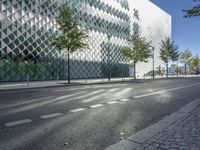a street with a few people on it and a building in the background with a diamond patterned glass structure