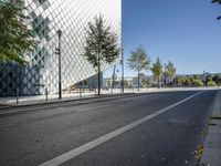 a street with a few people on it and a building in the background with a diamond patterned glass structure