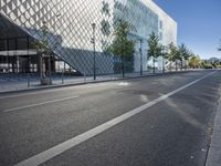 a street with a few people on it and a building in the background with a diamond patterned glass structure