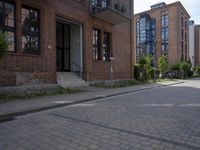 the sidewalk is brick with a planter in between the sidewalks to the side and a door leading out onto street