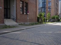 the sidewalk is brick with a planter in between the sidewalks to the side and a door leading out onto street