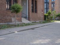 the sidewalk is brick with a planter in between the sidewalks to the side and a door leading out onto street