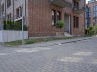 the sidewalk is brick with a planter in between the sidewalks to the side and a door leading out onto street