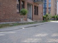 the sidewalk is brick with a planter in between the sidewalks to the side and a door leading out onto street