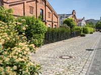 an alley with cobblestone roads and a building that is red brick and surrounded by trees