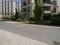 empty paved city street with two buildings in background, with cobblestone pavement and steps on sidewalk