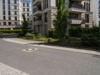 empty paved city street with two buildings in background, with cobblestone pavement and steps on sidewalk