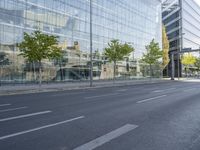 a bike parked on the side of a street in front of a glass building with trees on either side