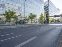 a bike parked on the side of a street in front of a glass building with trees on either side