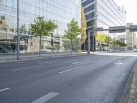 a bike parked on the side of a street in front of a glass building with trees on either side