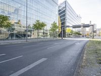 a bike parked on the side of a street in front of a glass building with trees on either side