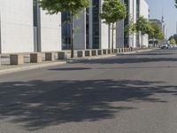 an empty sidewalk with a few trees on either side and one parked vehicle on the other