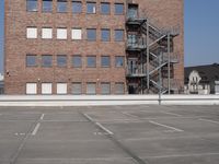 an empty parking lot with stairs and windows in the background with no parking signs on it