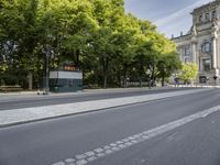 the view of an empty street with two buses in front of it and a building behind