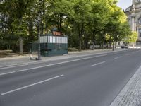 the view of an empty street with two buses in front of it and a building behind