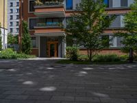 a residential driveway with a bench and bushes in between buildings and green grass on either side