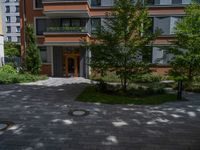 a residential driveway with a bench and bushes in between buildings and green grass on either side