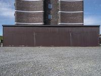 a building with a tower made of bricks is next to a park benches on gravel