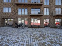 a motor cycle parked in front of a building and chairs and tables in the grass