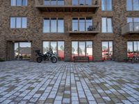 a motor cycle parked in front of a building and chairs and tables in the grass