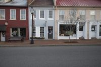 three stores on a street corner with a bench on the side and a fire hydrant in front