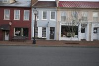 three stores on a street corner with a bench on the side and a fire hydrant in front
