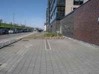 a brick and stone pavement with some grass next to buildings and cars in the background