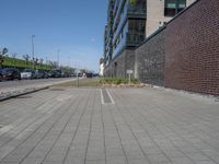 a brick and stone pavement with some grass next to buildings and cars in the background