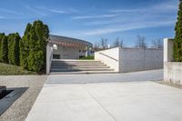 concrete steps and stairs leading to a building with trees in the background on a sunny day