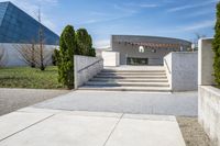 concrete steps and stairs leading to a building with trees in the background on a sunny day