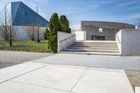 concrete steps and stairs leading to a building with trees in the background on a sunny day