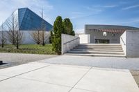 concrete steps and stairs leading to a building with trees in the background on a sunny day