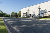 an empty street leading to a very big building with stairs on one wall and many windows and staircases on the second floor