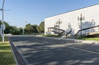 an empty street leading to a very big building with stairs on one wall and many windows and staircases on the second floor