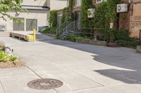 a paved sidewalk in an old, run down town neighborhood with a sidewalk sign on it