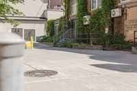 a paved sidewalk in an old, run down town neighborhood with a sidewalk sign on it