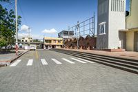 an empty city street with tracks coming into the ground with building facades in background with stairs leading up to the walkway, and people walking