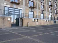 an empty parking lot in front of a tall apartment building with a balcony, balconies and balconies