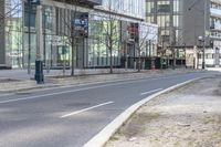 an empty road in the city near a building with a clock on it's side