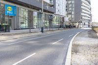 an empty road in the city near a building with a clock on it's side