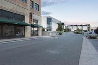 this is an empty street and the building in the back is a store front and a sidewalk with grass and rocks on each side