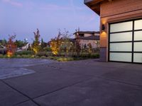 a home with large, gray doors in front of a yard and grass area at dusk